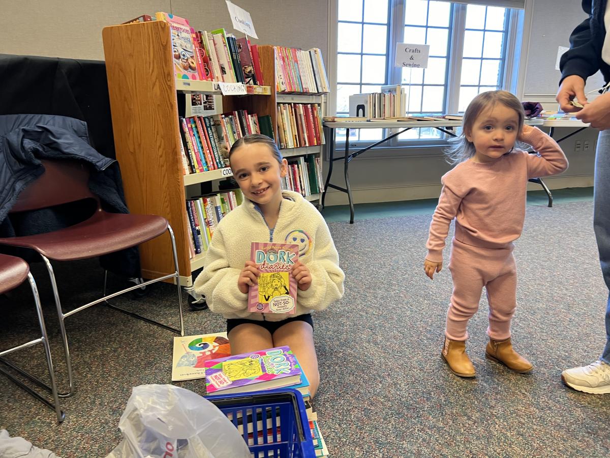 Grace Fonda, 9, of Monroe, shows off her new book as her little sister, Camilla, 2, looks on.